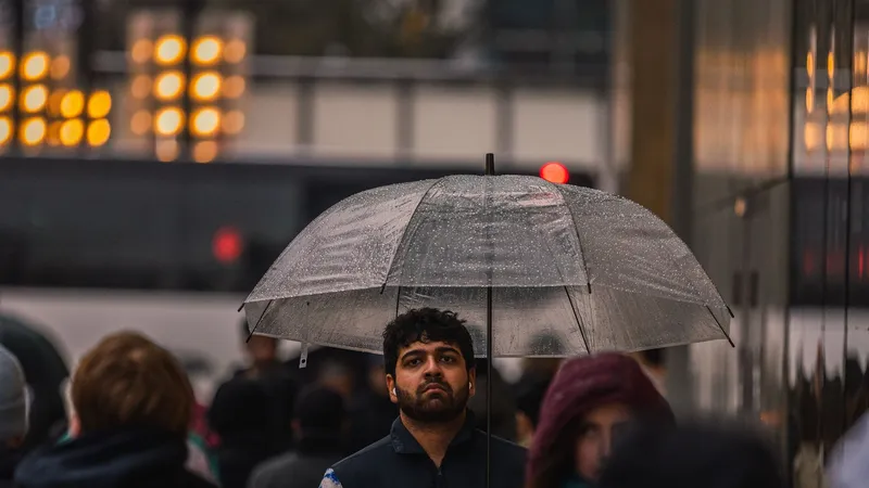 A man holding a clear umbrella walks through a crowd on a rainy evening in downtown Vancouver