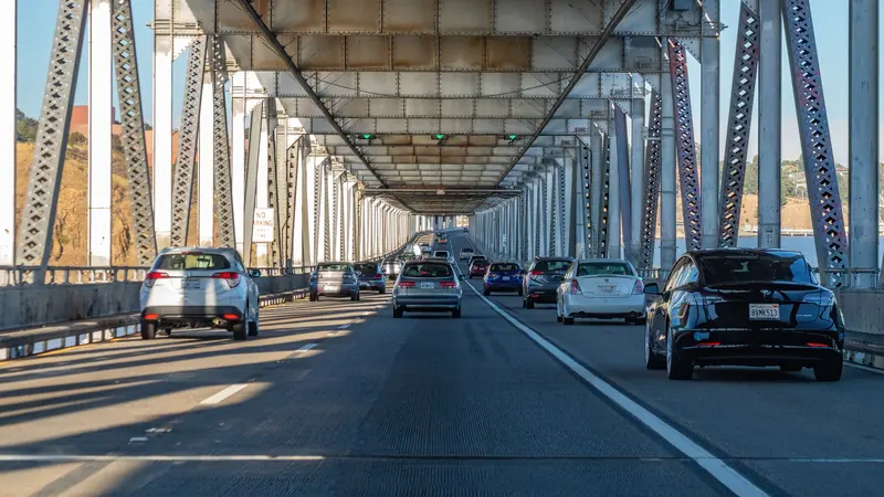 Cars crossing a steel truss bridge on a sunny day